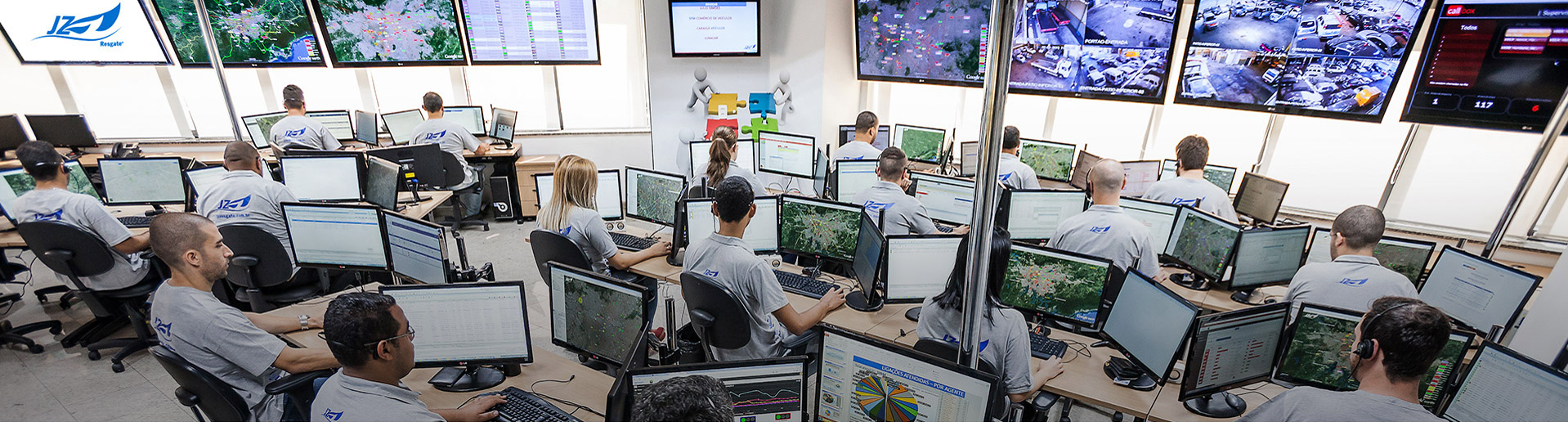 Central de monitoramento da JZ Resgate: equipe uniformizada em estações com vários monitores e telões com mapas